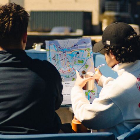 A shot of two people aboard the Amstel boat, one drives while the other shows the map
