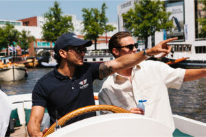 A skipper pointing out Amsterdam sights to guests aboard a 30-person sloop