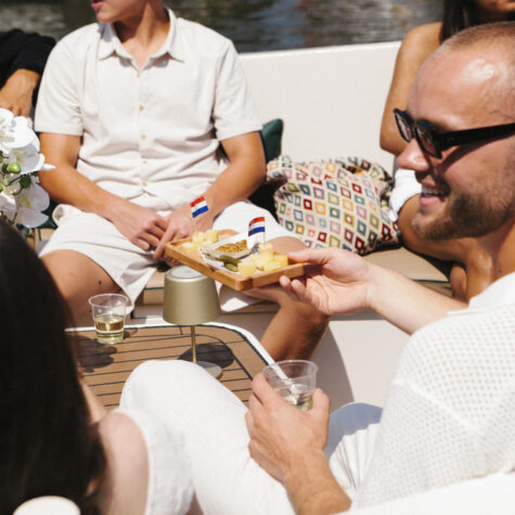 Een gast houdt een schaal met Nederlandse kaas vast aan boord van een privé-kaas- en wijncruise.
