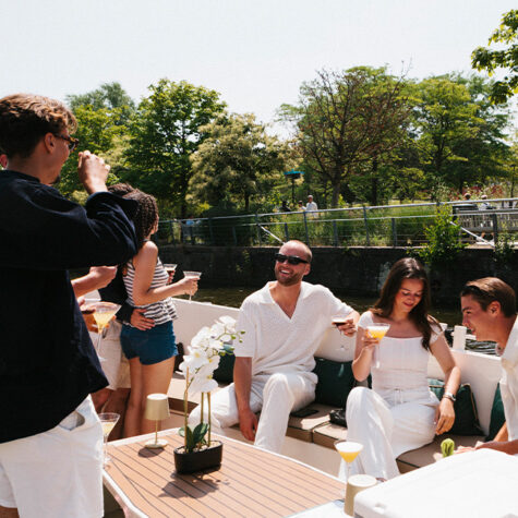 Gasten aan boord van een privé-rondvaartboot die in de zomer door de grachten van Amsterdam vaart.
