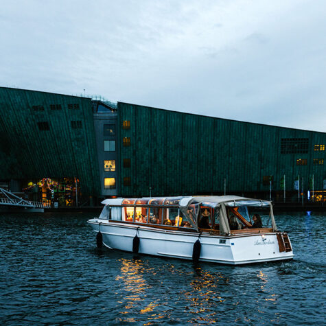 A small salon boat passing in front of the NEMO museum