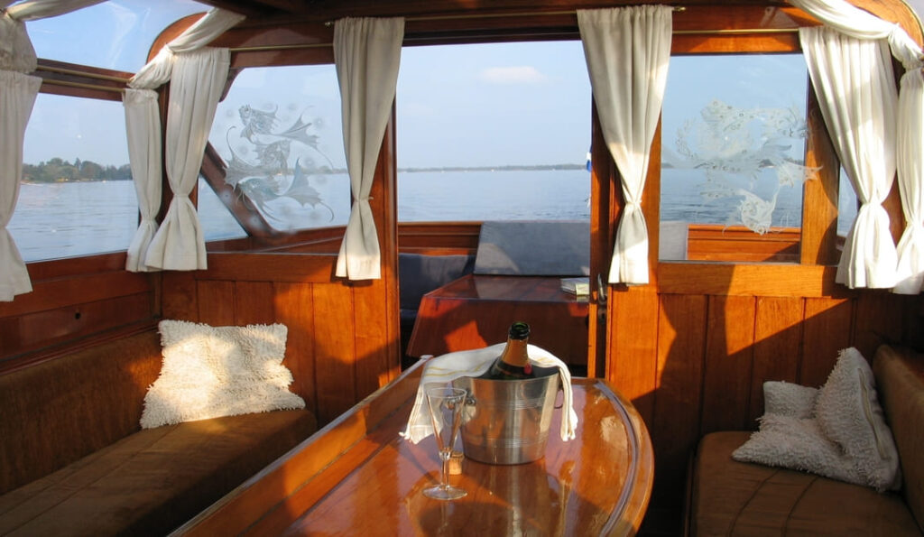 Interior of classic salon boat, with beautiful woodwork and bottle of chilled champagne on the table