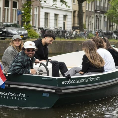Een groep vrienden die door de grachten van Amsterdam vaart