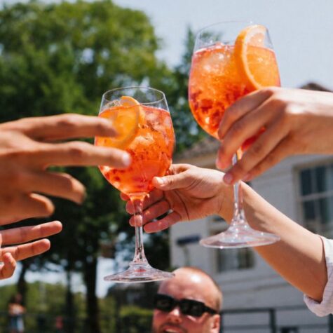 Een barman serveert twee spritzjes aan een gast aan boord van de Spritz Cruise