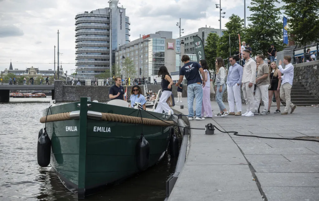 Een rondvaart met Eco Boats waarbij gasten aan boord gaan bij het vertrekpunt Centraal Station.