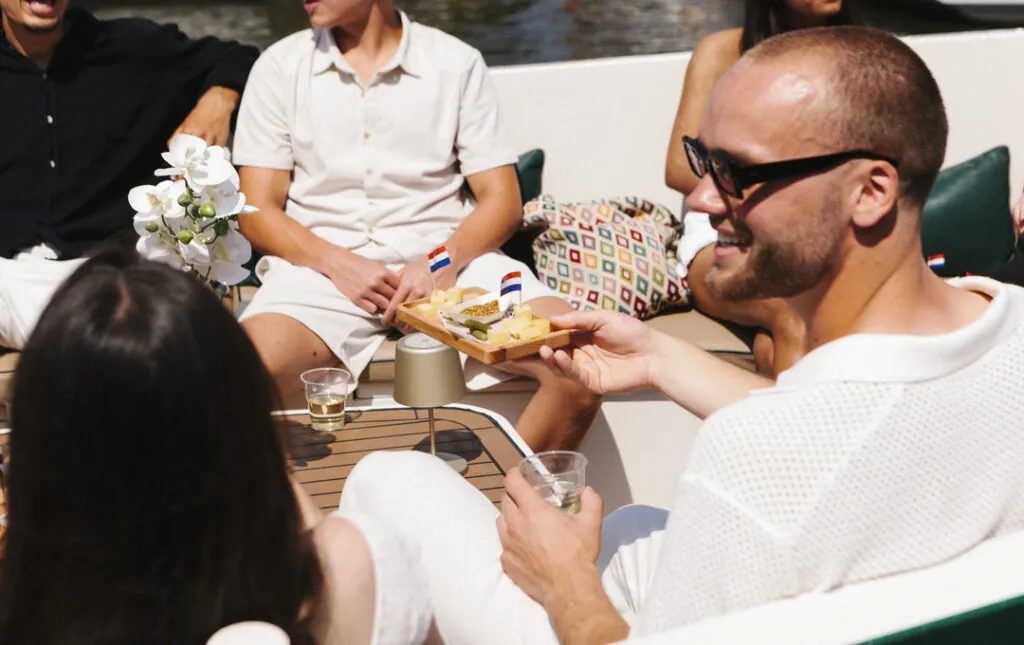 Een gast houdt een schaal met Nederlandse kaas vast aan boord van een privé-kaas- en wijncruise.